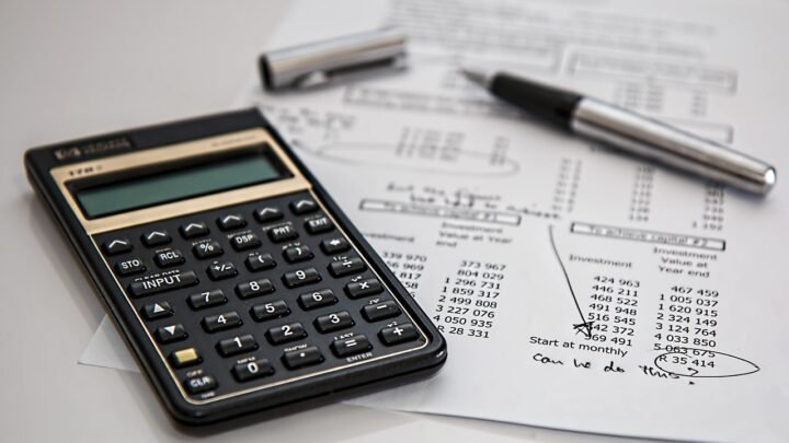 A calculator and pen on a desk, representing the process of allocating a monthly marketing budget