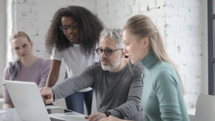 B2B marketing team reviewing a keyword research spreadsheet on a laptop in a meeting room