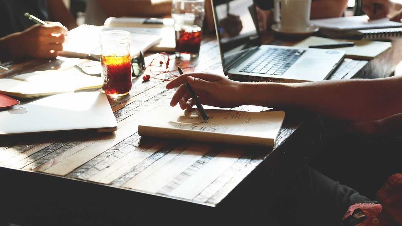 Small marketing team meeting around a table, representing the handful of generalists who typically staff a full-service digital marketing agency retainer