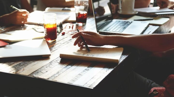 Small marketing team meeting around a table, representing the handful of generalists who typically staff a full-service digital marketing agency retainer