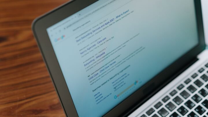 Close-up of a laptop screen showing a Google search bar with autocomplete suggestions dropping down