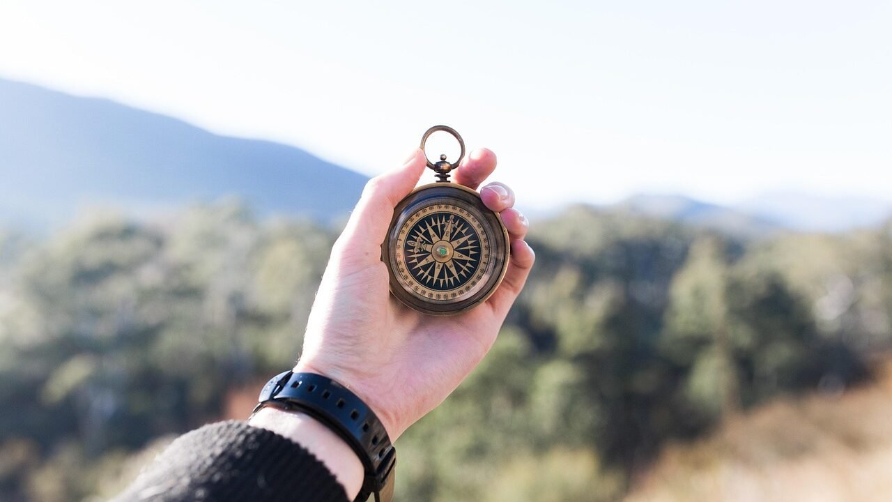 A hand holding a compass outdoors, symbolizing choosing a career direction in marketing