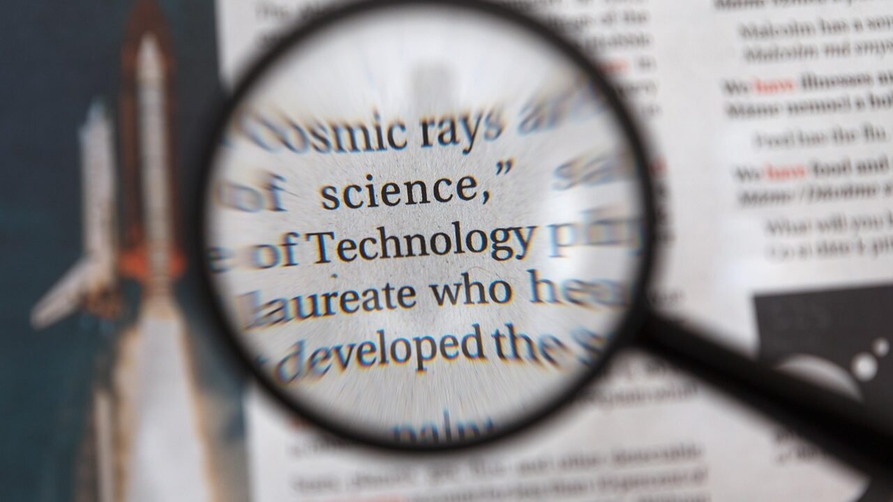 A magnifying glass held over a printed document, representing manual keyword and content research