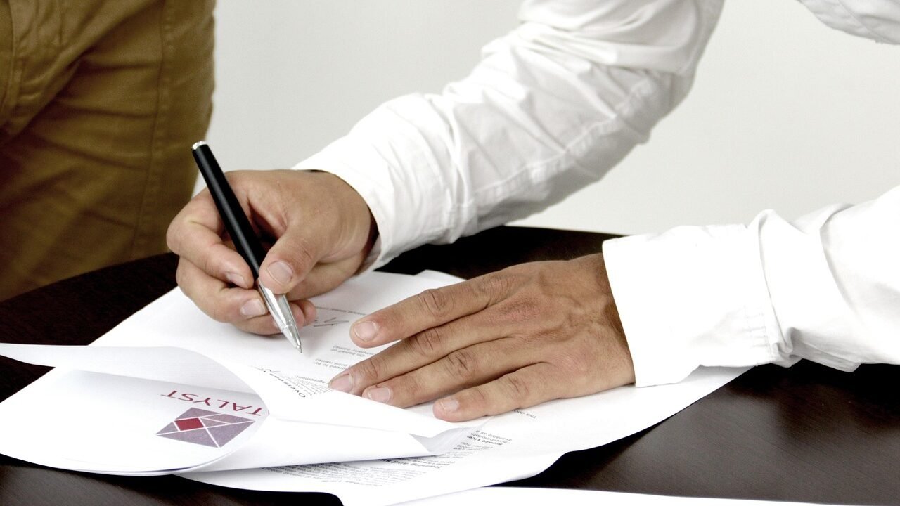 Businessperson signing a contract document, representing the choice between an SEO retainer and a project-based agreement