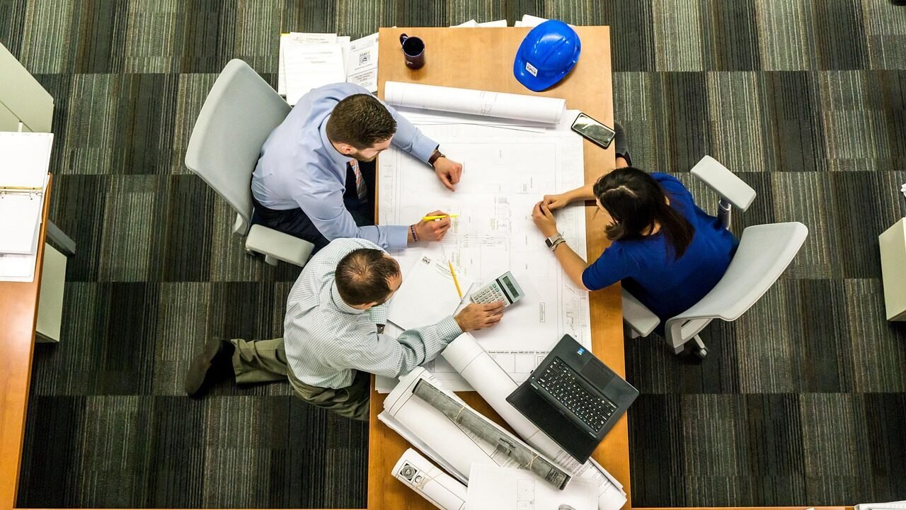 Small team of three professionals collaborating around a table planning marketing strategy in an office