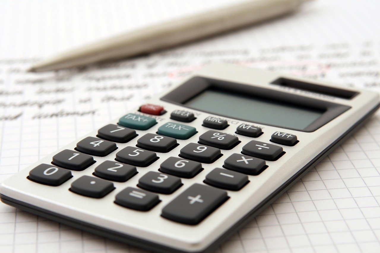 Calculator and financial documents representing a startup founder planning a marketing budget by funding stage