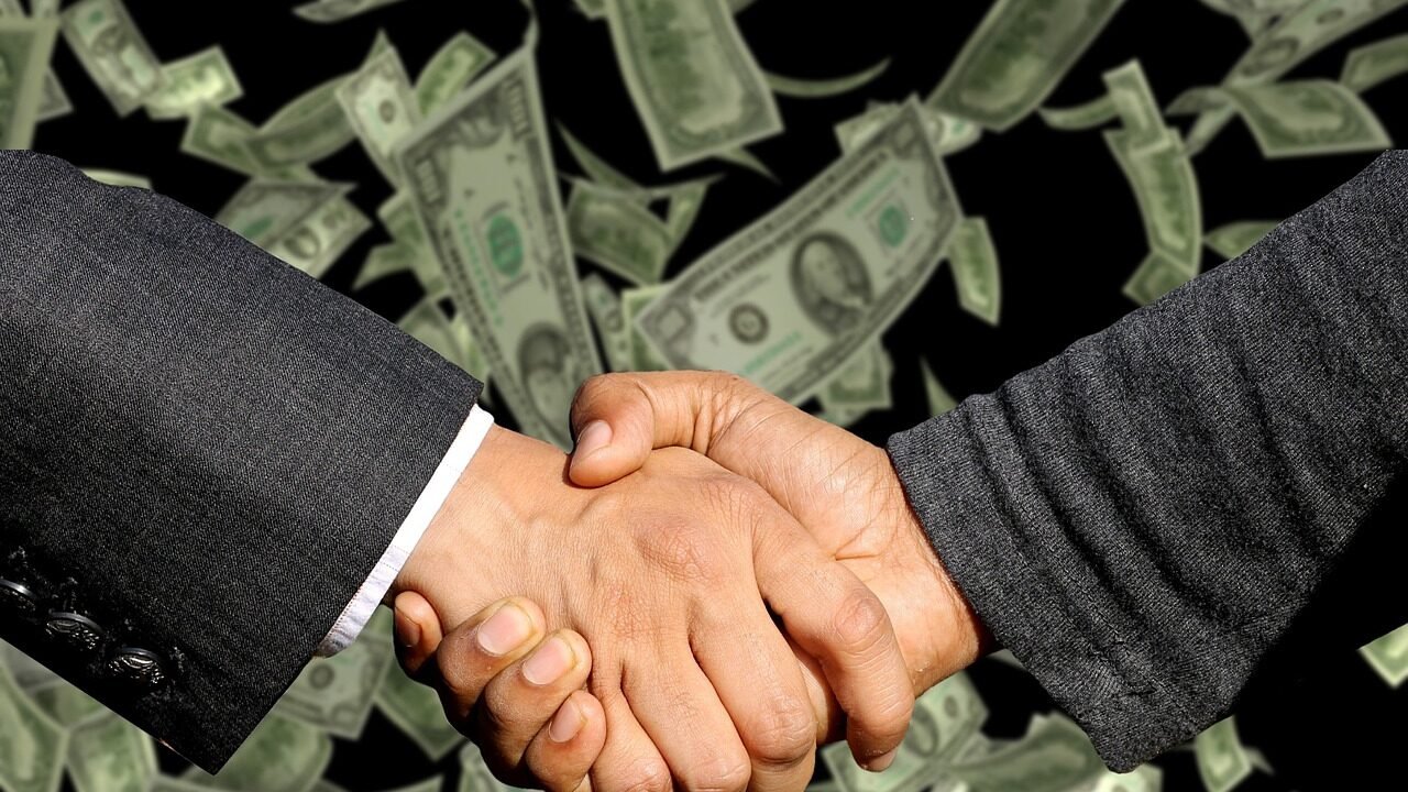Two business people shaking hands over a contract, representing a handover between SEO agencies