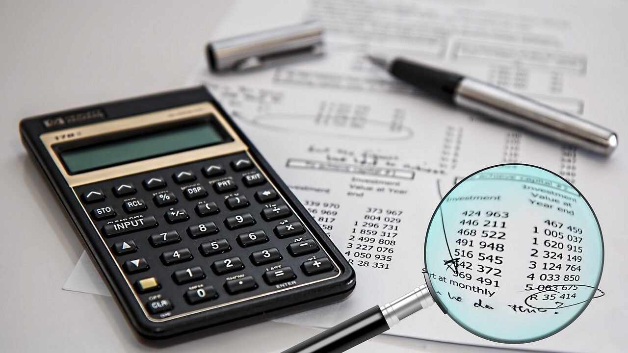 A magnifying glass over a document with financial figures, representing a close examination of a website during an SEO audit.